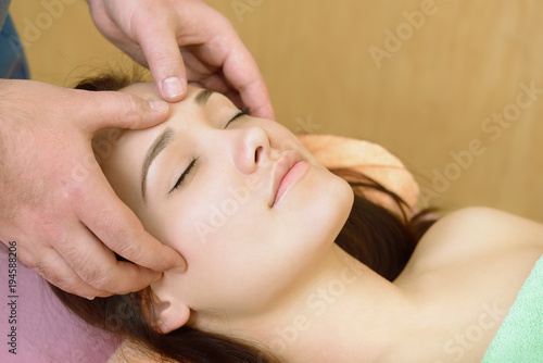 Body care. Face massage. Beautiful young woman relaxing with hand massage at beauty spa salon.
