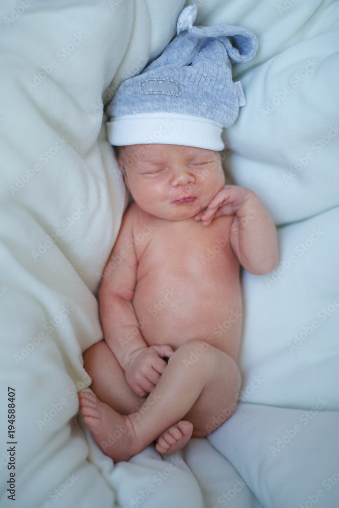 Sleeping baby in a blue cap in bed Sleeping baby in a blue cap in bed