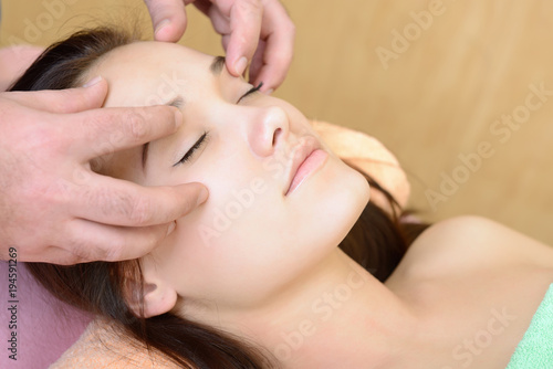 Body care. Face massage. Beautiful young woman relaxing with hand massage at beauty spa salon.