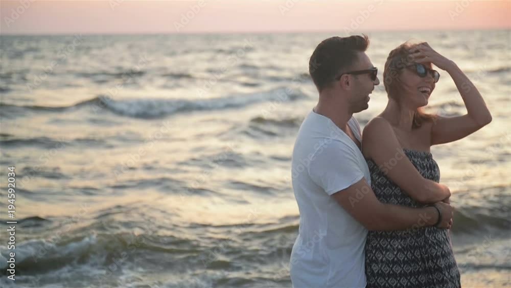 Portrait of Hansome Boyfriend Hugging His Blonde Girlfriend Standing Near the Sea During Sunset. Portrait of Hansome Boyfriend Hugging His Blonde Girlfriend Standing Near the Sea During Sunset.