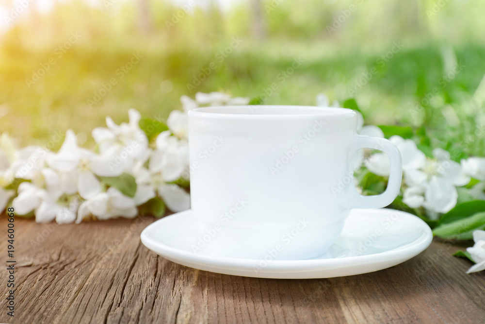 White mug and apple flowers on a wooden background. Side view White mug and apple flowers on a wooden background. Side view