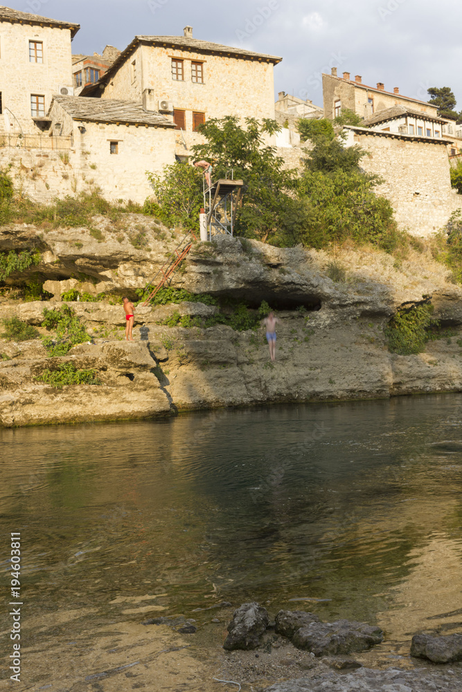 People diving into Neretva river in Mostar at sunset time