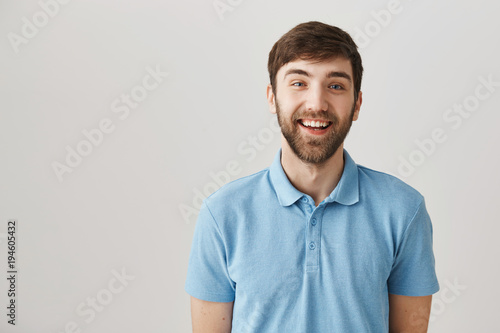 I am trully happy. Adorable caucasian bearded man with moustache in blue polo shirt  smiling broadly at camera and being in good mood. Cheerful guy once again tries to ask popular colleague on date