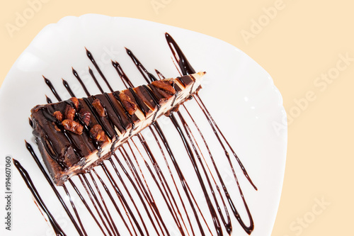 Chocolate cheesecake with pecan and chocolate syrup on a plate isolated on white top view. photo