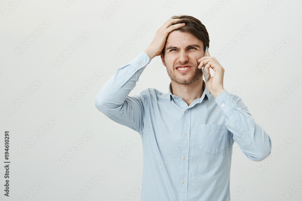 Oh no, it slipped my mind. Studio shot of attractive young entrepreneur in casual shirt punching forehead with palm and talking on smartphone, grimacing as recalling about important thing he forgot Oh no, it slipped my mind. Studio shot of attractive young entrepreneur in casual shirt punching forehead with palm and talking on smartphone, grimacing as recalling about important thing he forgot