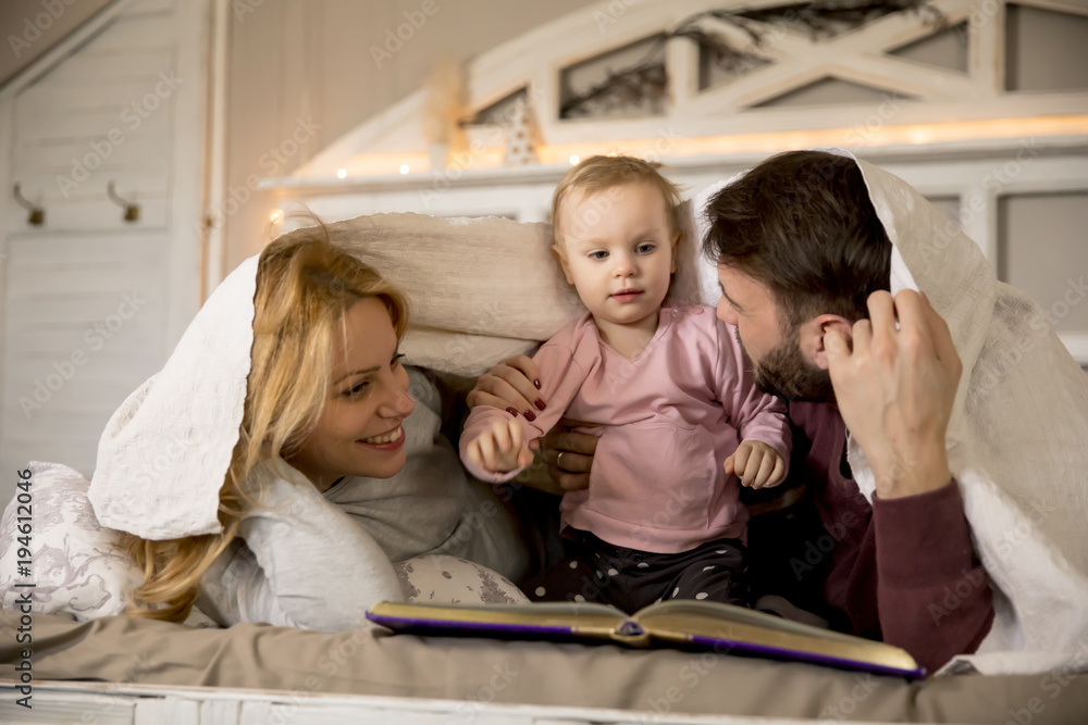 Obraz premium Young family having fun on the bed