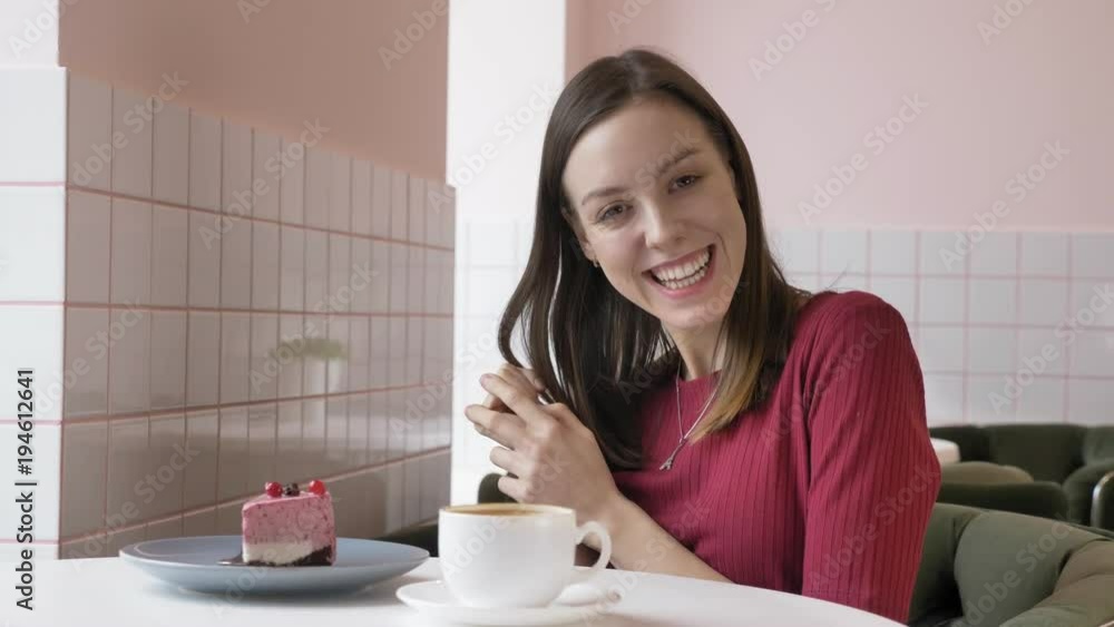 Young beautiful brunette girl smiling and looking at camera in cafe, natural portrait. 60 fps Young beautiful brunette girl smiling and looking at camera in cafe, natural portrait. 60 fps