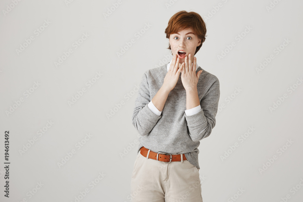 Oh my, look at time, I am late. Portrait of emotive good-looking redhead with short haircut and freckles, holding hands near opened mouth, lifting eyebrows from astonishment and surprise Oh my, look at time, I am late. Portrait of emotive good-looking redhead with short haircut and freckles, holding hands near opened mouth, lifting eyebrows from astonishment and surprise