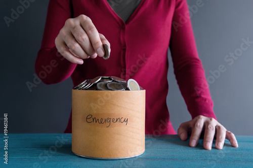 Saving Money for Emergency Concept. Woman putting Coin into a Box photo