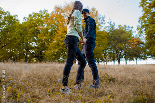 Young couple holding hands on a sunday afternoon going for a walk in the forest, in autumn season. © vladteodor