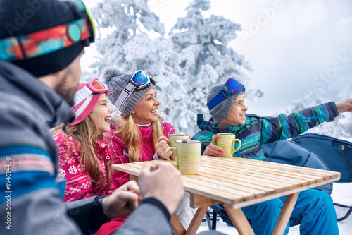 Family laughing and enjoying in hot drink at ski resort