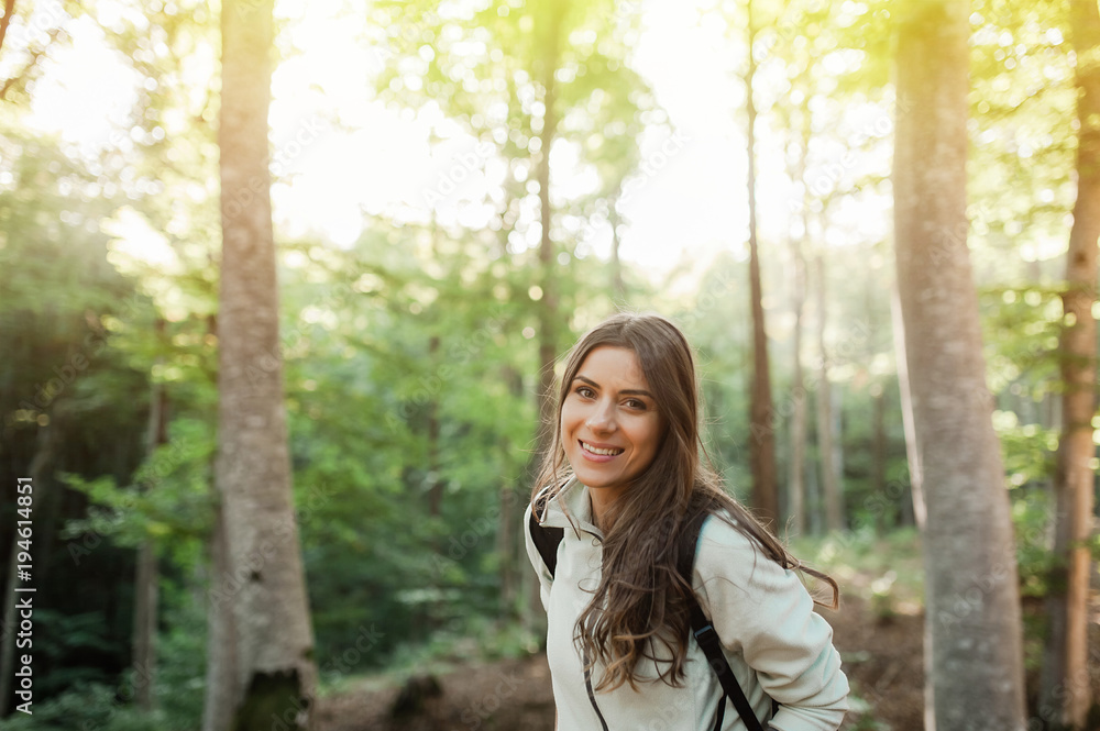 Pretty young woman smiling happy carrying backpack in the forest on sunset light in the autumn season. Pretty young woman smiling happy carrying backpack in the forest on sunset light in the autumn season.