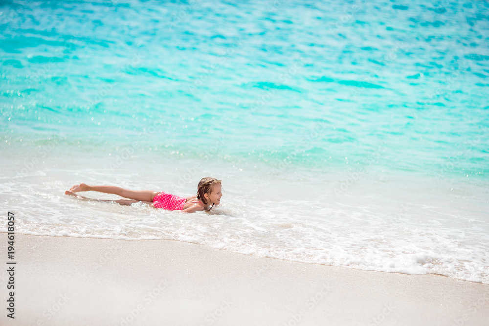 Adorable little girl at beach having a lot of fun in shallow water