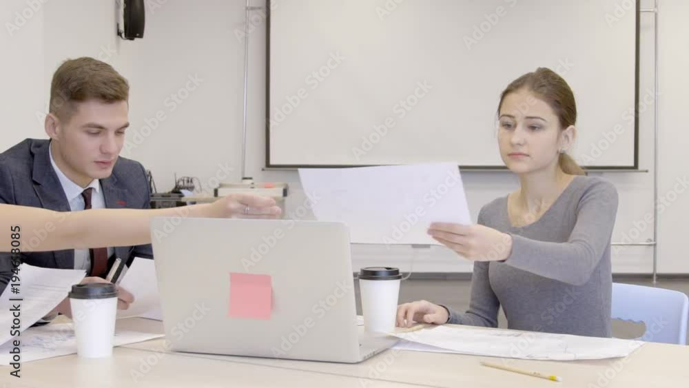 Financial analytics are giving paper reports with bitcoin graphs on to female boss in modern office. Investors are sitting at the big wooden table in conference room and working together on the Financial analytics are giving paper reports with bitcoin graphs on to female boss in modern office. Investors are sitting at the big wooden table in conference room and working together on the