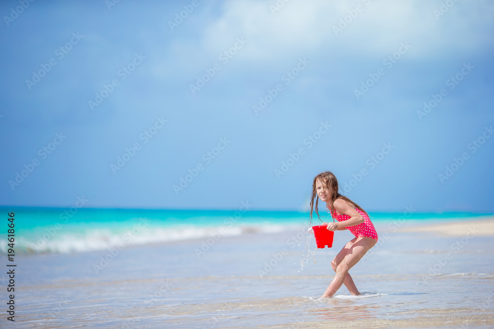 Adorable little girl playing with beach toys in shallow water Adorable little girl playing with beach toys in shallow water