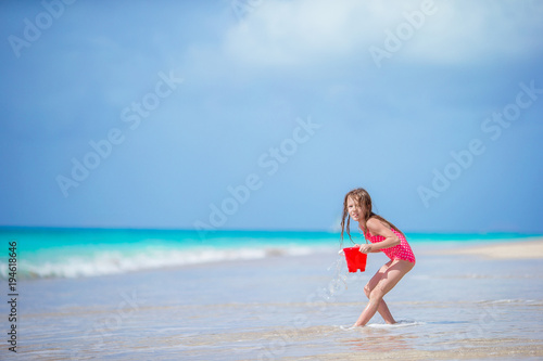 Adorable little girl playing with beach toys in shallow water