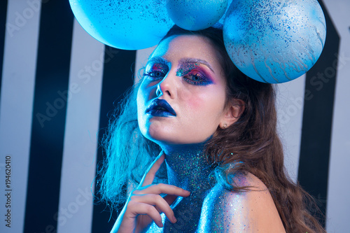 Young attractive girl in makeup, in glasses and balloons on the head