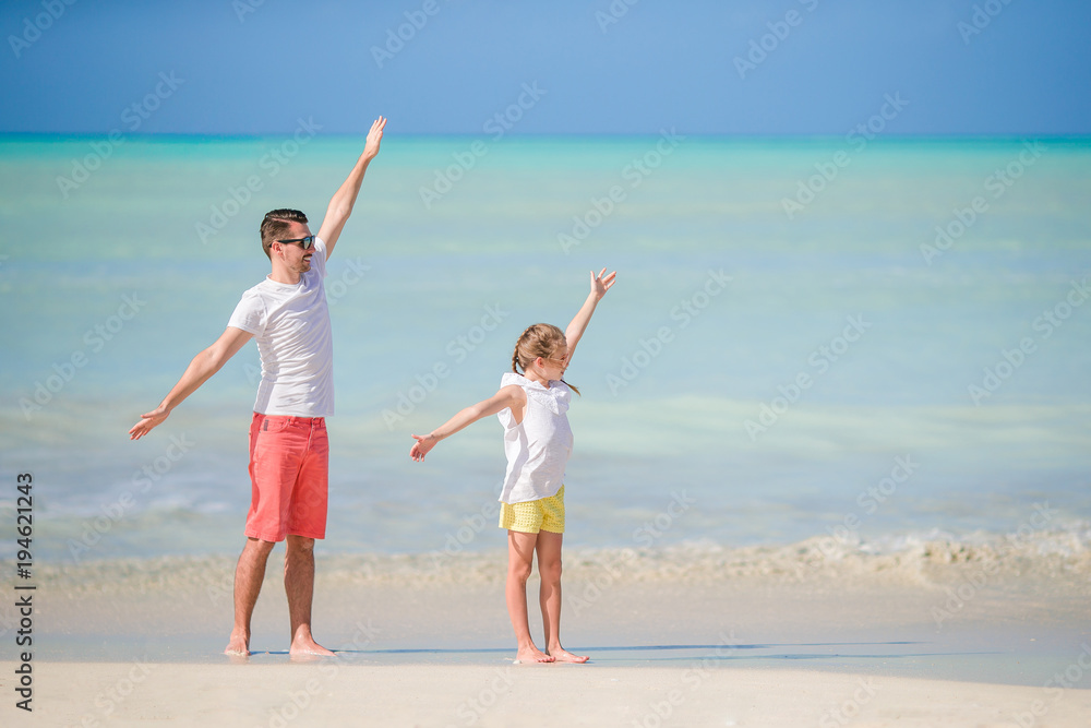 Little girl and happy dad having fun during beach vacation Little girl and happy dad having fun during beach vacation