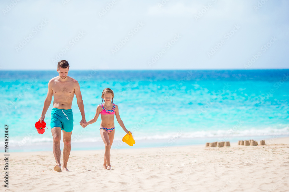 Little girl and happy dad playing on the beach