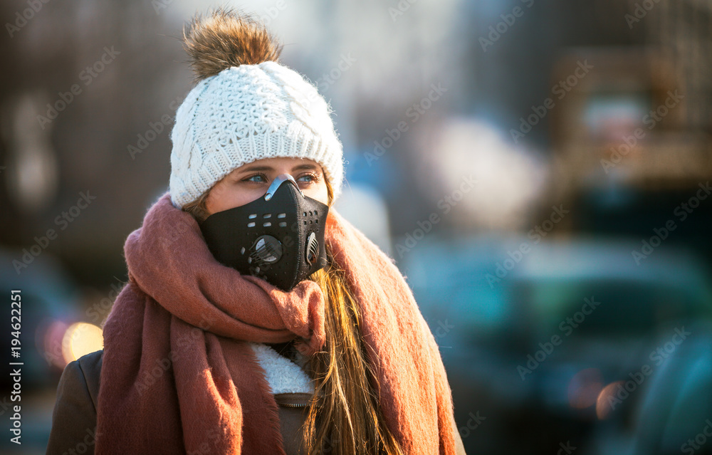 Plakat Młoda kobieta jest ubranym maskę ochronną w ulicie miasta, smogu i zanieczyszczeniu powietrza