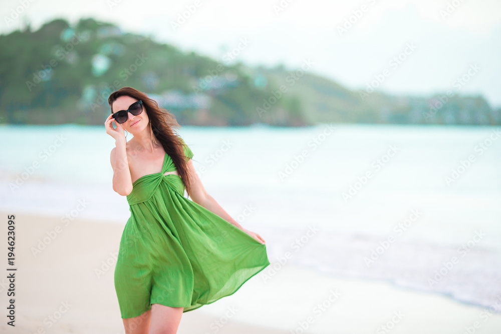 Young beautiful woman having fun on tropical seashore. Happy girl walking at white sand tropical beach Young beautiful woman having fun on tropical seashore. Happy girl walking at white sand tropical beach