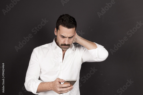 Young handsome man using a mobile phone with a negative attitude
