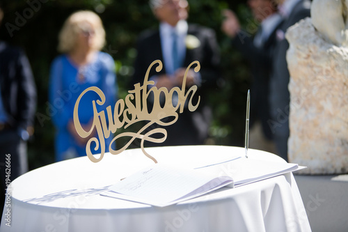 фотографія Gold Wedding Guestbook Sign with Guests in Background