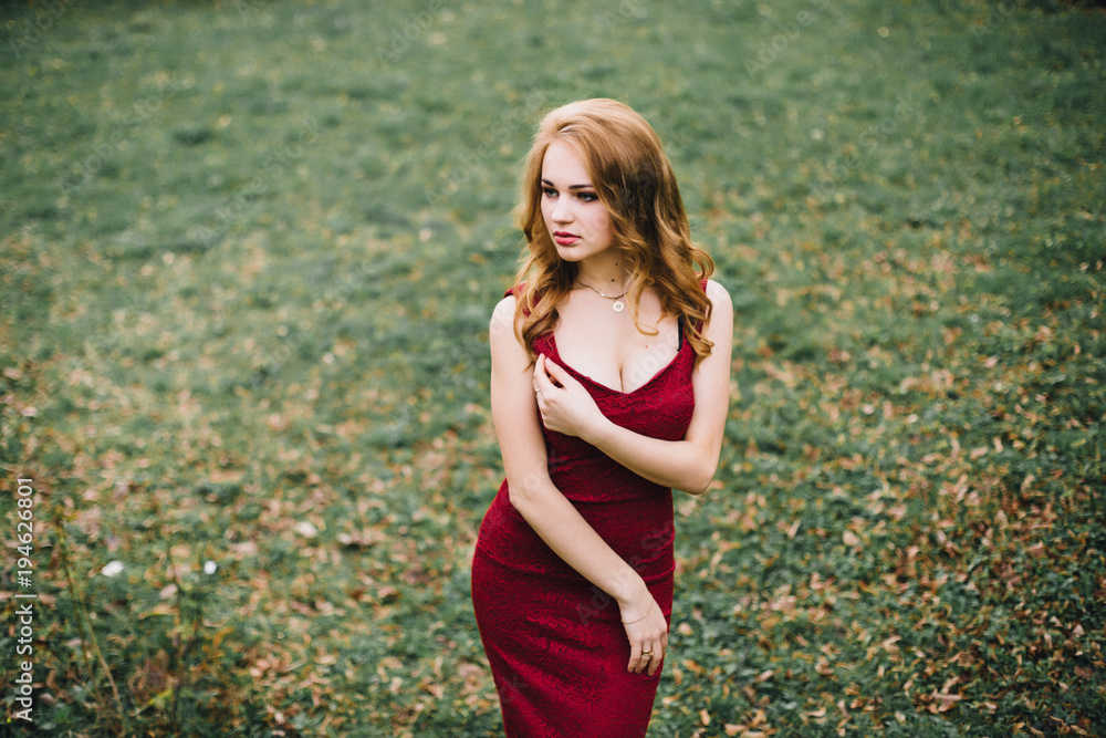 Beautiful girl in the flowering cherry blossom. In a burgundy dress with beautiful hair and makeup Beautiful girl in the flowering cherry blossom. In a burgundy dress with beautiful hair and makeup