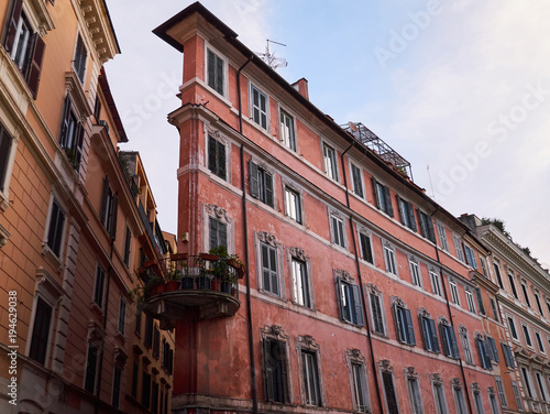 Old narrow dirty pink residential building with round balcony. Rome, Italy