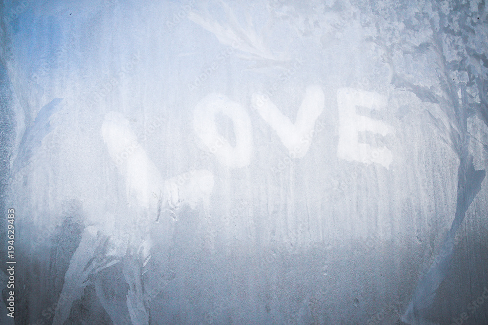 Love inscription on the frozen window in winter patterns in winter