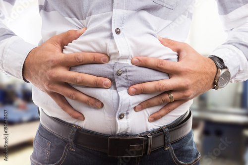 Man pressing bloated abdomen or belly as cramp flatulence problem. photo