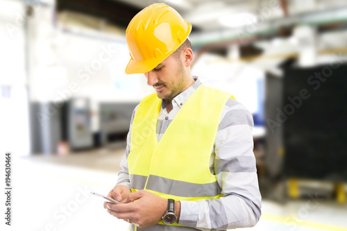 Factory worker employee chatting browsing texting on smartphone.