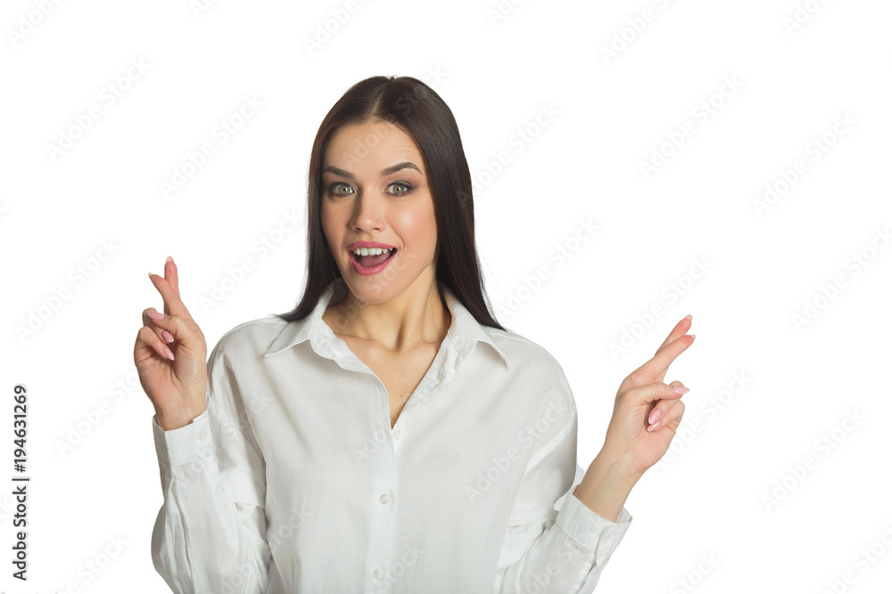 beautiful young joyful girl with a smile in a white shirt on a white background showing fingers happiness beautiful young joyful girl with a smile in a white shirt on a white background showing fingers happiness