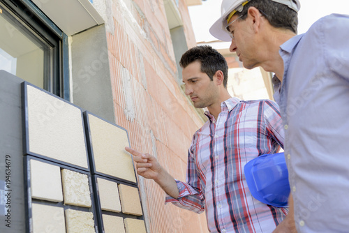 Two men looking at exterior wall finishes