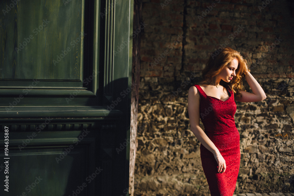 elegant, beautiful girl on the background of green doors. In a burgundy dress with beautiful hair and makeup elegant, beautiful girl on the background of green doors. In a burgundy dress with beautiful hair and makeup