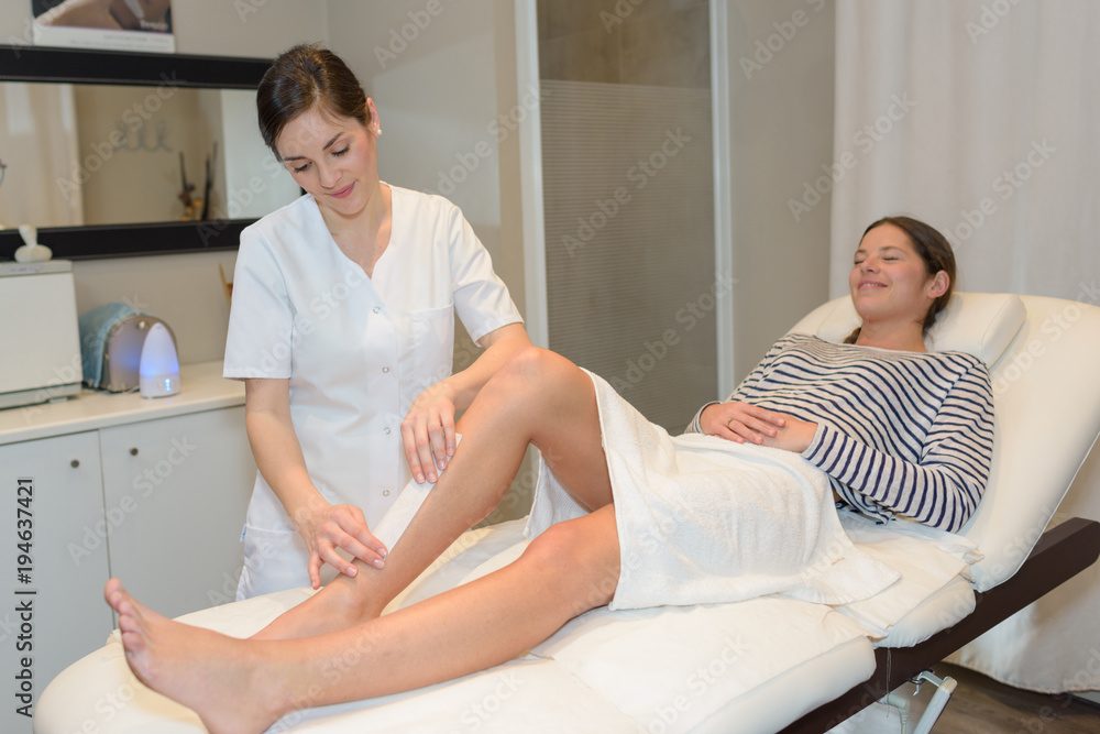 Obraz premium beautiful lady cosmetician providing procedure of leg hair removal