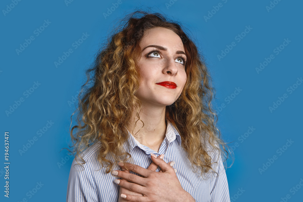 Isolated shot of beautiful dreamy glad young female looking up with pleasure and gratitude, keeping hands on her chest, smiling happily, feeling thankful, grateful or relieved about something Isolated shot of beautiful dreamy glad young female looking up with pleasure and gratitude, keeping hands on her chest, smiling happily, feeling thankful, grateful or relieved about something