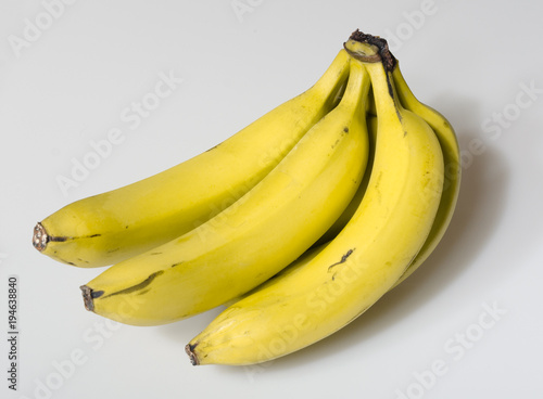 A beautiful bright yellow bunch of ripe bananas isolated on a white studio background. healthy vivid colours.