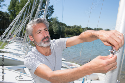 attractive middle-aged man preparing sport sailboat