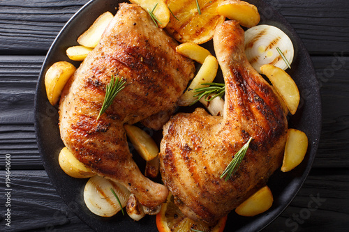 grilled chicken leg with oranges, onions and potatoes macro. Horizontal top view photo