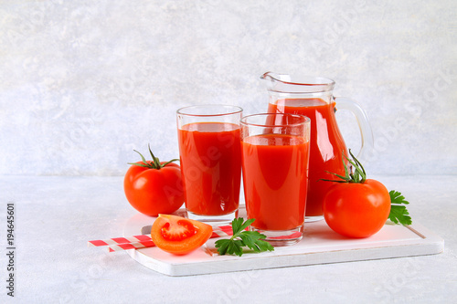 Tomato juice in glasses and a pitcher on a gray concrete table. © detry26
