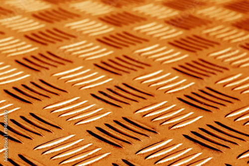 Diamond shaped metal floor pattern with blur in orange tone.