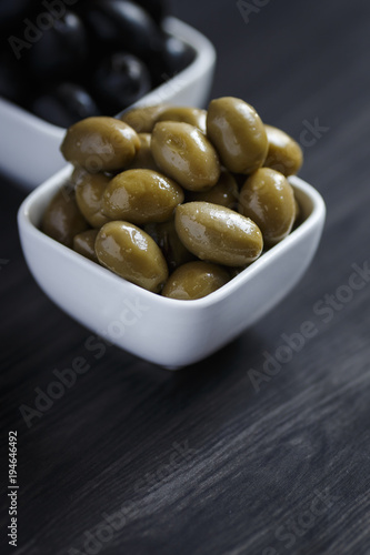 Olives in a white bowl on a dark wooden table