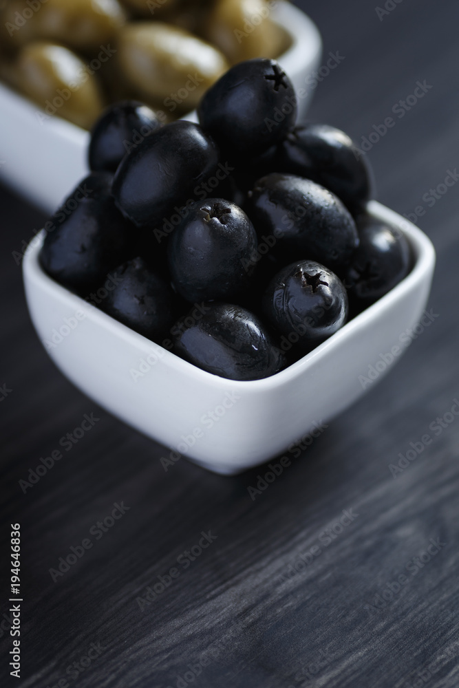 Olives in a white bowl on a dark wooden table Olives in a white bowl on a dark wooden table