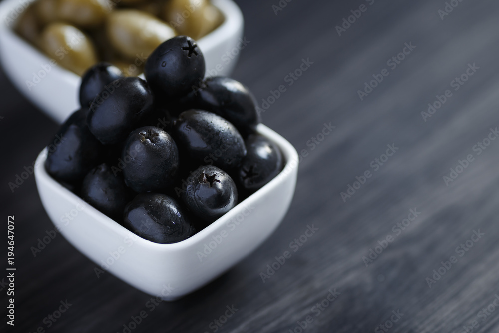 Olives in a white bowl on a dark wooden table Olives in a white bowl on a dark wooden table