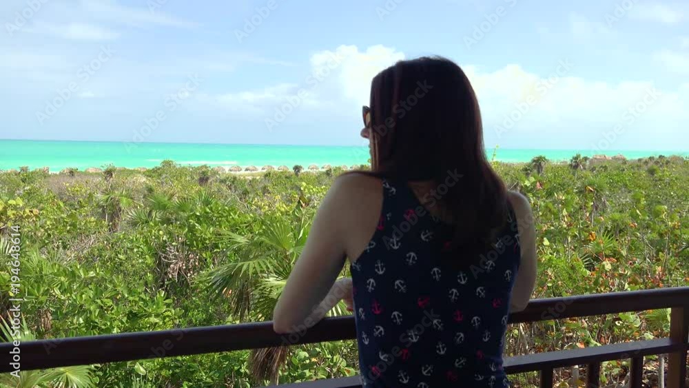 A young woman on vacation looks out at the ocean on a beautiful sunny day. A young woman on vacation looks out at the ocean on a beautiful sunny day.