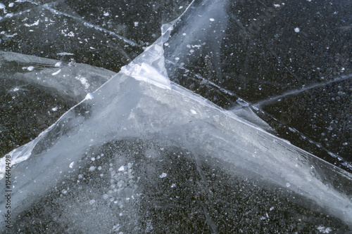 cracks in thick solid layer of ice of a frozen lake