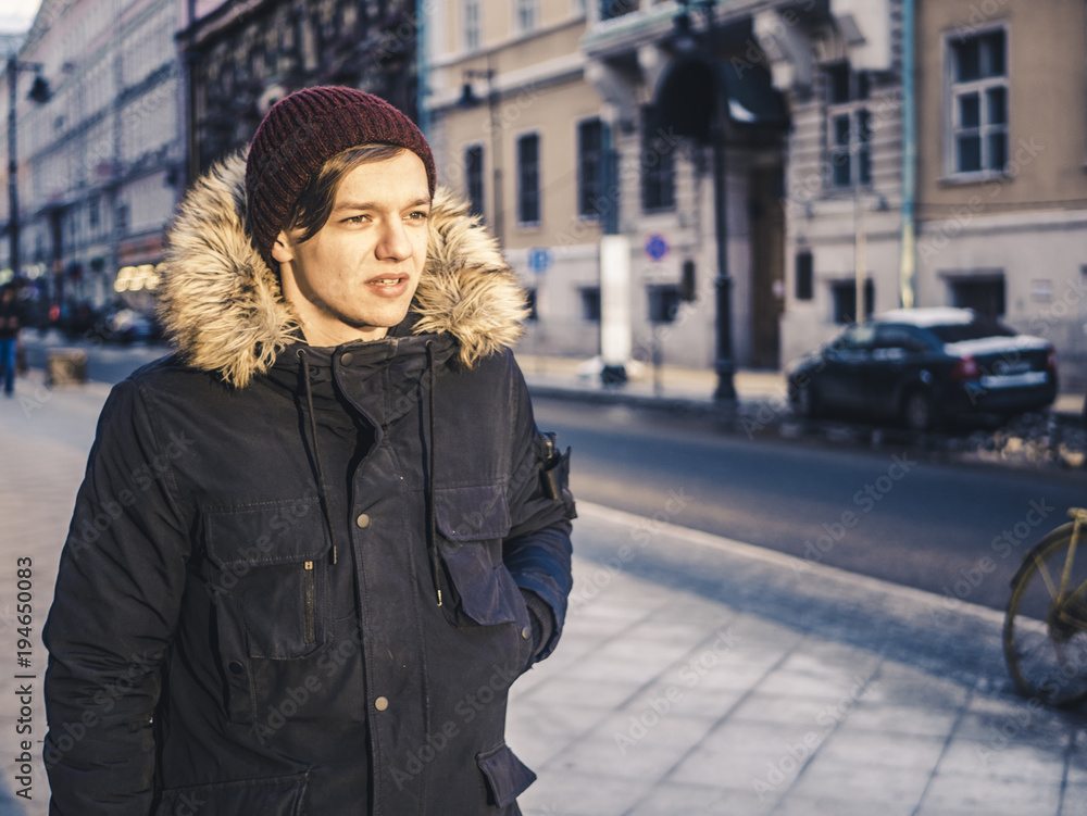 Fototapeta premium adult long hair man in jacket walking in the europe street on a winter day