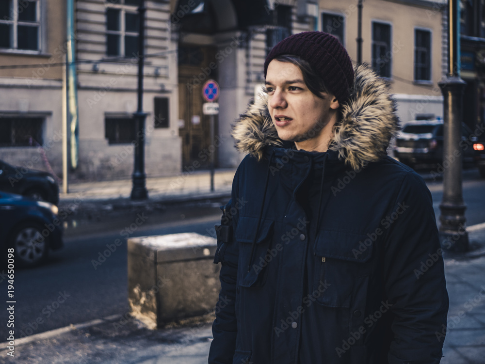Fototapeta premium adult long hair man in jacket walking in the europe street on a winter day