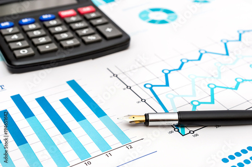 Pen with calculator on the financial graphs. Business concept.